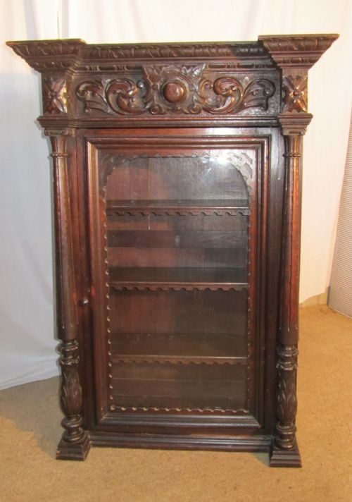 a tall glazed french carved oak bookcase