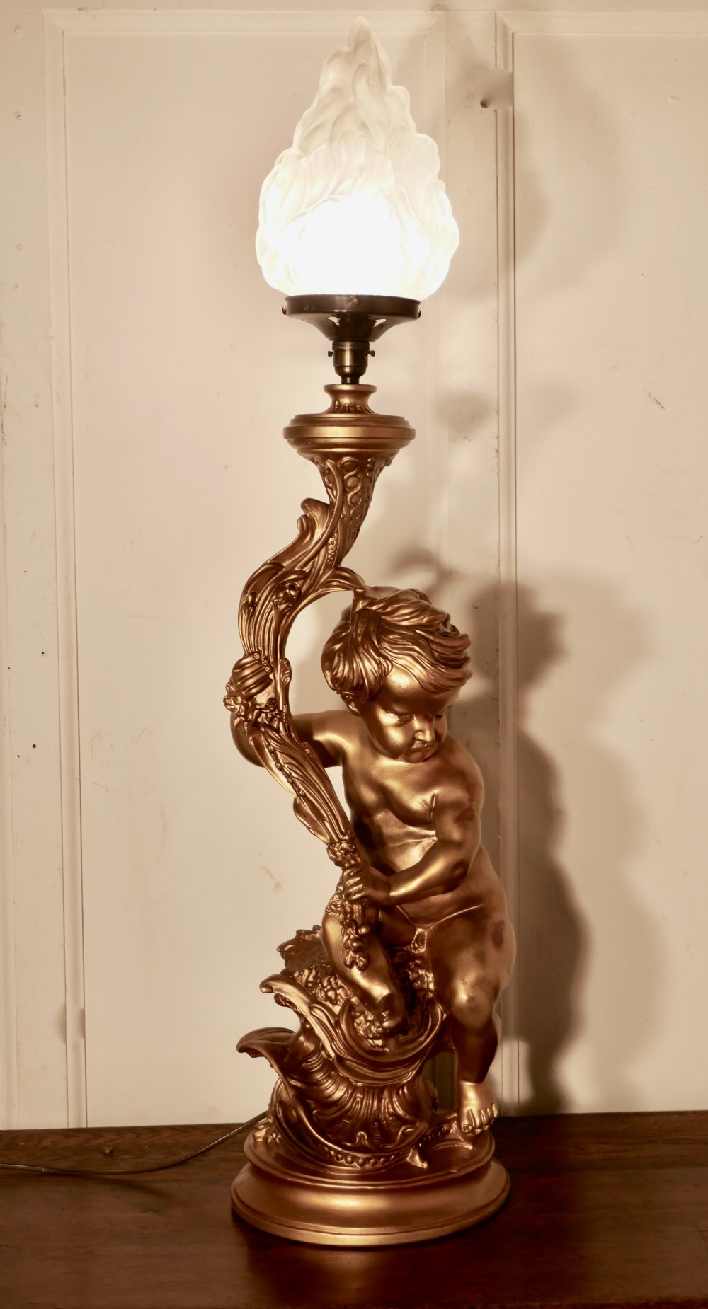 a very large gilt table lamp in the form of a cherub or putti