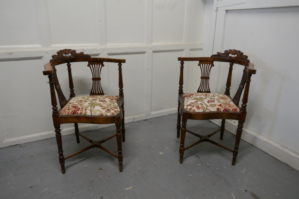 a pair of edwardian walnut corner arm chairs