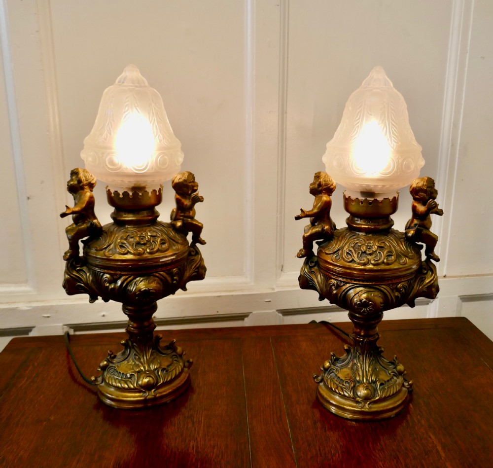 a pair of 19th century french gilt lamps in the form of cherubs or putti