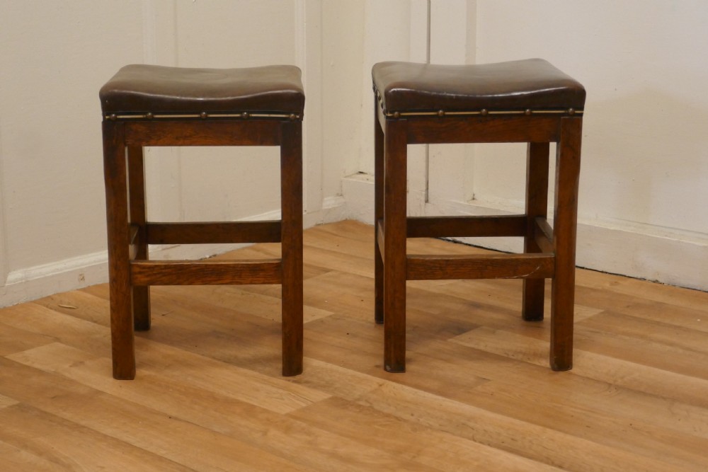 a pair of arts and crafts golden oak and leather stools