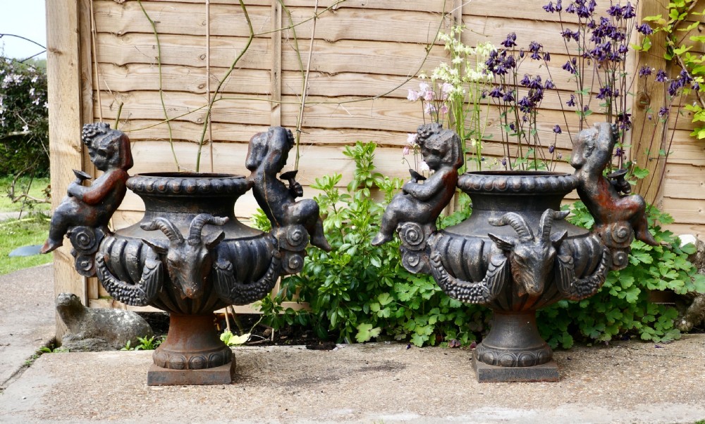 pair of large cast iron garden urns with rams and putti