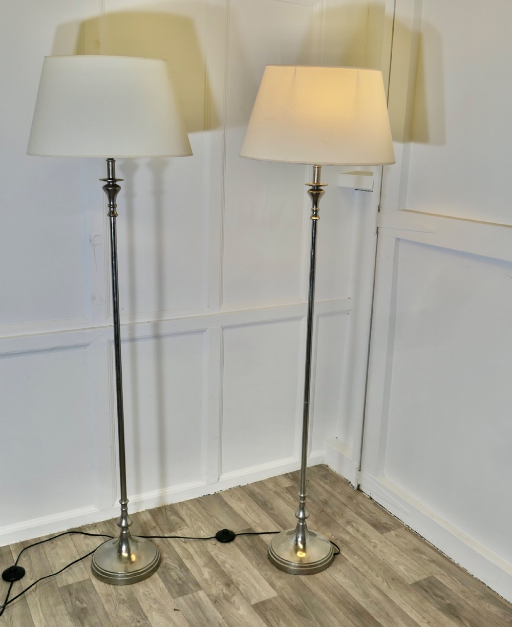 a pair of silver floor lamps with shades